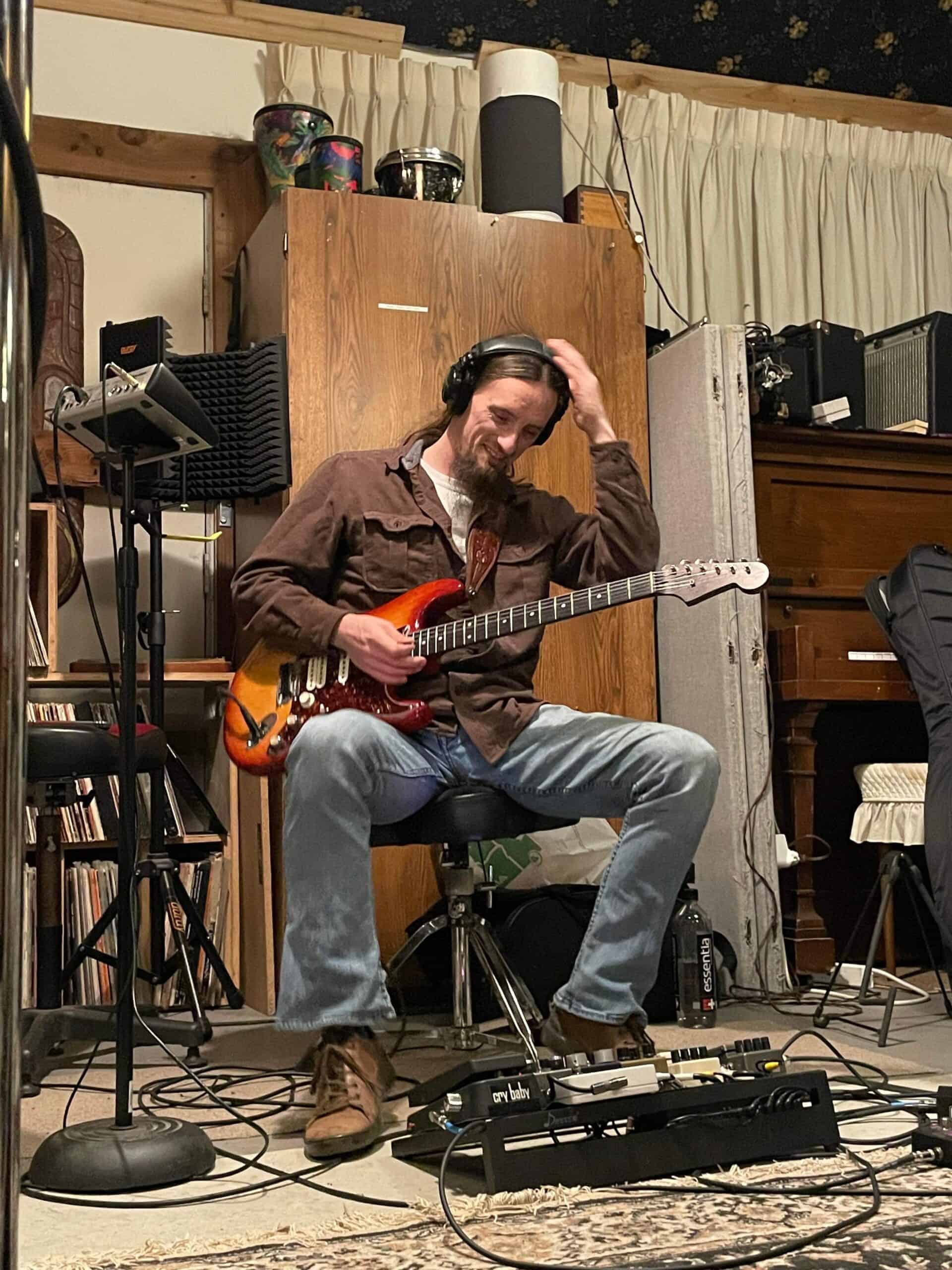 Picture of Brandon getting ready to record guitar in a recording studio.